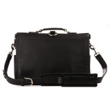 This is the back of a leather briefcase that has a shoulder strap laying on the ground.