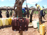 This is a red brown full grain leather briefcase at a well in Uganda.