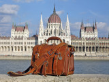 This is a red brown full grain leather briefcase in front of parliament in Budapest, Hungary.