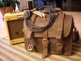 This is a full grain leather briefcase with a harmonica and amp next to it.