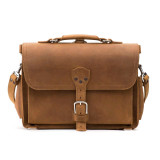 This is a front picture of a tan brown leather briefcase that has a strap in the center.