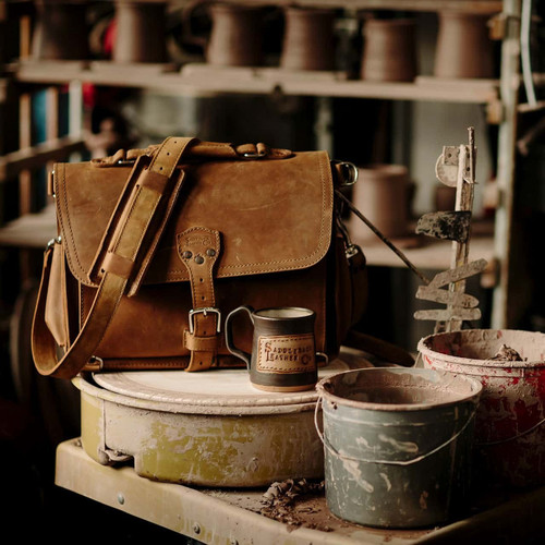 This is a picture of a tan brown leather briefcase in a potters studio.