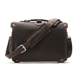 This is the back of a dark brown slim leather briefcase that has a strap laying in front of it.