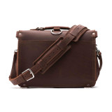 This is the back of a slim red brown leather briefcase with its shoulder strap laying in front of it.