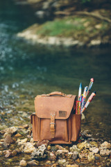 The back picture of the tan brown leather backpack with fireworks in the side pocket.