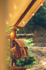 This light brown leather backpack is hanging from a pole.