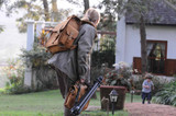 A woman photographer is wearing a leather backpack  in Africa and her son is running towards her.