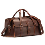 This is a red brown leather duffle bag that has three straps to close it and has two round handles from the front side.