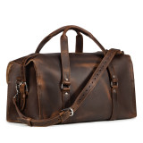This is a dark brown leather duffle bag that has three straps to close it and has two round handles from the front.