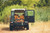 This is a tan brown leather duffle bag in the back of a green land rover defender.