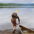 This is a dark brown leather duffle bag with three straps on the front as a man's backpack while he is pulling the canoe.