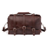 This is a red brown leather duffle bag with three straps on the front and folded over on top. It is filled with overnight travel gear and the duffle is looking straight into the camera.