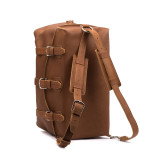 This is a tan brown leather duffle bag with the shoulder strap that is used as backpack straps.