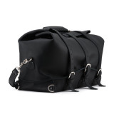 This is the side of a black leather duffle bag that has three straps and is folded over the top to hold in the overnight travel gear.