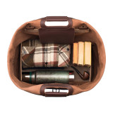 This tan brown leather duffle bag is open and it shows that it holds a whole lot of stuff.