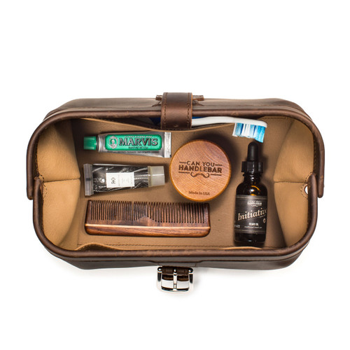This is a dark brown leather toiletry bag on the opened and loaded.