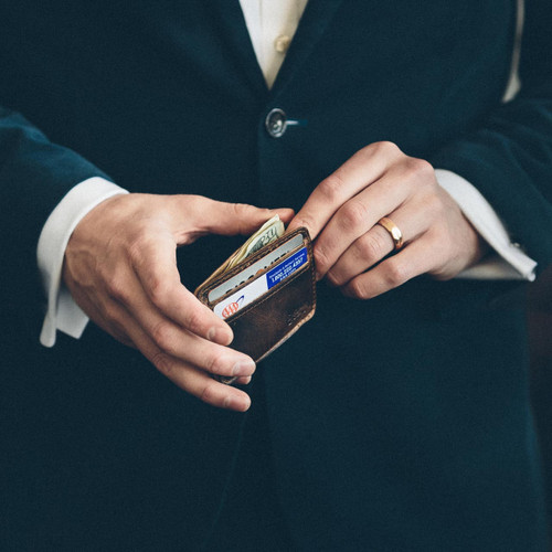 This is a man holding a thin leather wallet.