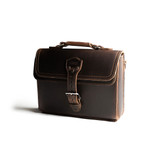 This is the front side of a dark brown leather satchel with a front pocket angled.