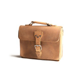 This is the front side of a tan brown leather satchel with a front pocket.