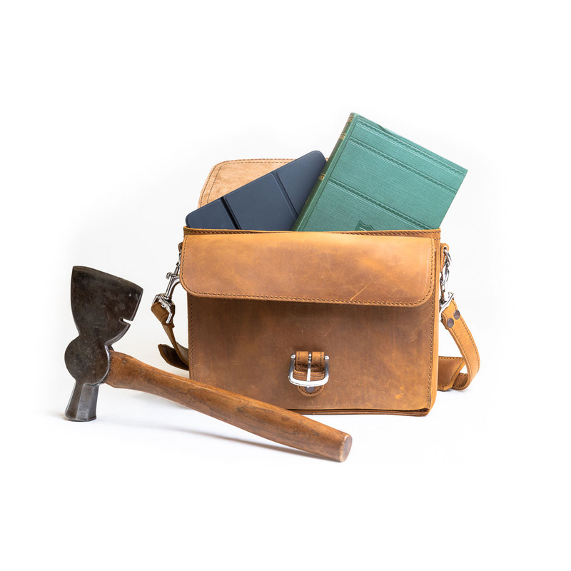 This is the front side of a tan brown leather satchel with a front pocket empty.