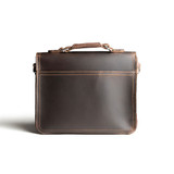 This is the back side of a dark brown leather satchel with a front pocket.
