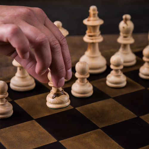 These are chess pieces being moved on a leather travel chess set.