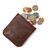 This is a red brown leather coin purse that has change spilling out of the pouch.