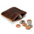 This is a dark brown leather coin purse that has change spilling out in front of the pouch.