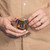 This is the front of a tan brown leather coin purse used for change that a man is holding.