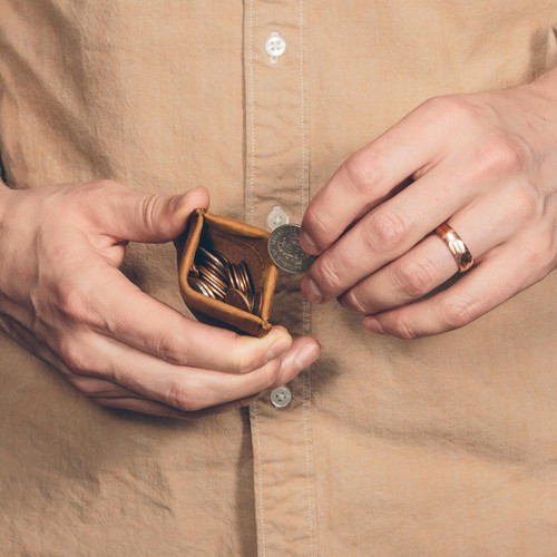 This is the front of a tan brown leather coin purse used for change that a man is holding.