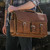 This is a man holding the brown leather briefcase as a laptop bag.