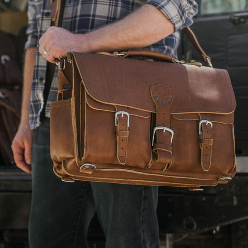 This is a man holding the brown leather briefcase as a laptop bag.