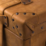 This is a leather trunk that will be a vintage antique one day in a museum. This is the corner. It is a tan brown steamer trunk that was old time luggage back in the day on trains and ships.