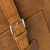 This is a leather trunk that will be a vintage antique one day in a museum. This is the a buckle and strap. It is a tan brown steamer trunk that was old time luggage back in the day on trains and ships.