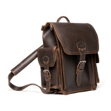 This is a squared dark brown leather backpack with an old phone behind the side pocket.