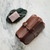 This is a red brown leather toiletry bag on the top side on snow.