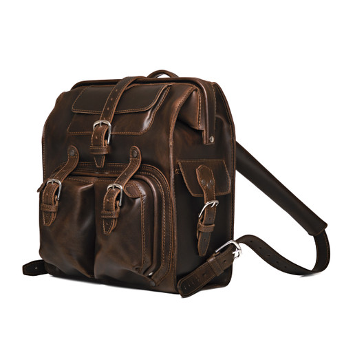 Big mouth leather backpack from the side in the color dark coffee brown. Buckle and gladstone closure keep the bag shut. Made by Saddleback