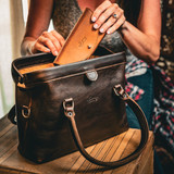 A leather purse with a Gladstone closure shown open.