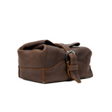 Angled view of the dark coffee brown leather toiletry dry bag buckled shut. Made by Saddleback