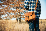 Here is a model standing in front of a tree with the rounded satchel in tobacco on. Made by Saddleback
