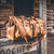 Here is the tobacco deep pocket duffle bag on the steps in front of a cabin. Made by Saddleback