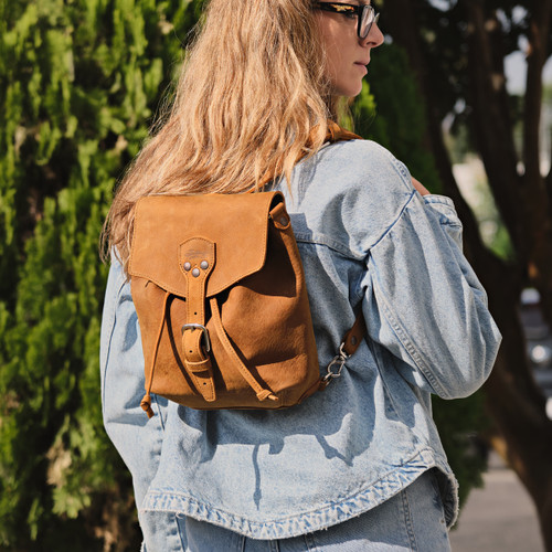 Tobacco leather 10" tumbled drawstring backpack outdoors on a woman model. Made by Saddleback