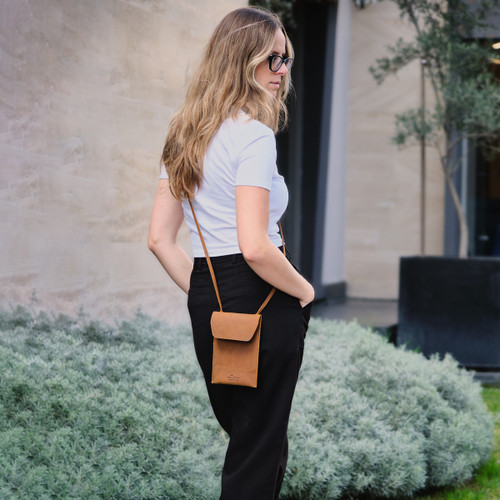 Tobacco colored leather walkers pouch on a female model outside. Made by Saddleback